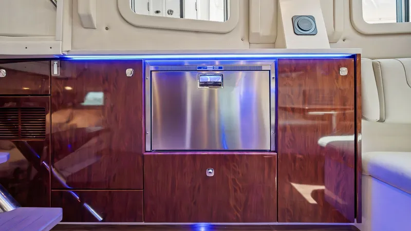 Slide: The Image of Galley with Stainless Steel Appliances This image showcases the modern galley of the 2022 Formula 430 Super Sport Crossover, featuring high-gloss wood cabinetry and a sleek stainless steel refrigerator. Ambient blue LED lighting enhances the sophisticated atmosphere, while the efficient layout - 7030624