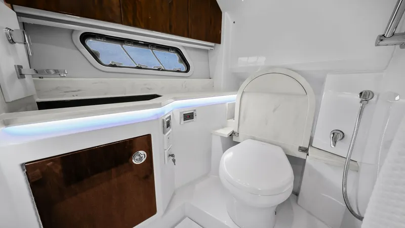 Slide: The Image of Modern Bathroom with Premium Fixtures This sleek bathroom on the 2022 Formula 430 Super Sport Crossover features elegant wood cabinetry and a stylish countertop. The space is equipped with a modern toilet, a compact shower, and ambient LED lighting, offering both functionality and luxury. A w - 7030625