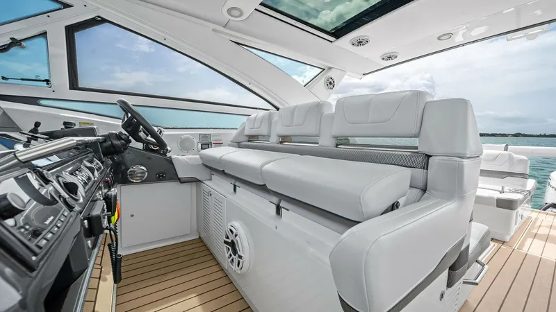 Slide: The Image of Helm and Cockpit Seating Area The helm of the 2022 Formula 430 Super Sport Crossover showcases an elegant and modern design with state-of-the-art controls. The spacious cockpit seating area features plush, white upholstery for comfort and style, complemented by a sleek, teak-look floo - 7030613