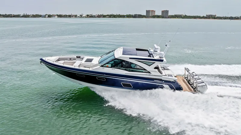 Slide: The Image of Dynamic Side View Underway The Formula 430 Super Sport Crossover, Blue Agave, glides effortlessly across the water, showcasing its sleek, modern design. The deep blue hull contrasts beautifully with the white cabin and accents, while the powerful engines create an impressive wake. - 7030639