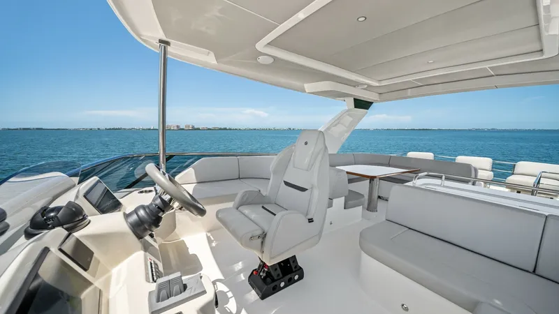Slide: The Image of Spacious Flybridge with Helm Station The Absolute Navetta 58's flybridge offers a commanding helm station equipped with advanced navigation systems, providing excellent visibility. The spacious seating area features plush, light-colored upholstery, perfect for relaxation and socializing whil - 7018661