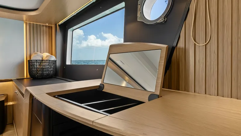 Slide: The Image of Galley with Ocean View Window The galley of the Absolute Navetta 58 showcases a sleek, modern design with high-end wooden finishes and a large window offering stunning ocean views. The integrated sink and ample counter space provide functionality and style, while the porthole adds a c - 7018632