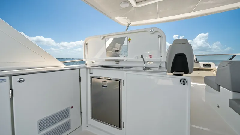Slide: The Image of Flybridge Wet Bar Area This image showcases the sleek and functional wet bar area on the flybridge of the 2026 Absolute Navetta 58. Featuring a modern sink with a protective cover and a convenient under-counter refrigerator, this space is perfect for entertaining guests while e - 7018662