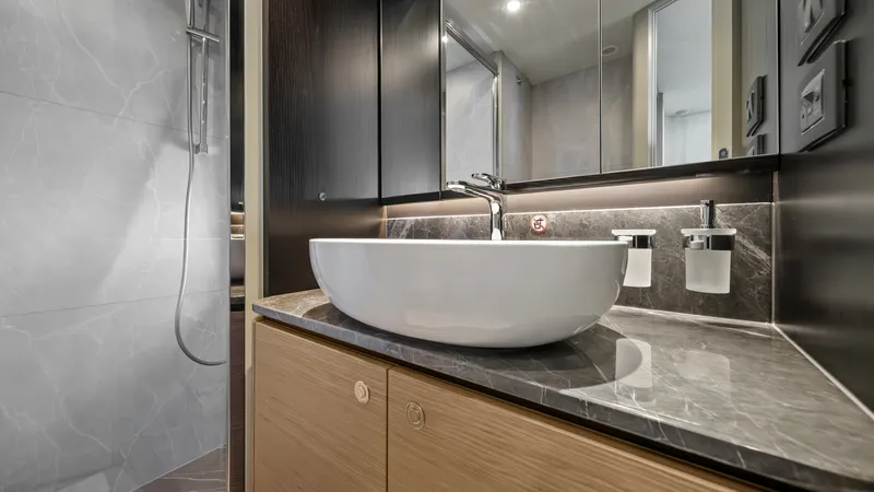 Slide: The Image of Luxurious En-Suite Bathroom The en-suite bathroom of the Absolute Navetta 58 showcases a sleek design with a modern vessel sink atop a polished marble countertop. The elegant cabinetry provides ample storage, while the glass-enclosed shower offers a luxurious experience. Subtle ligh - 7018650