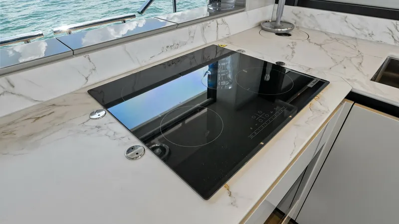 Slide: The Image of Galley with Induction Cooktop This image showcases the sleek galley of the 2026 Absolute Navetta 58, featuring a modern induction cooktop set into a luxurious marble countertop. Clean lines and high-end finishes make this space both functional and stylish, perfect for gourmet cooking - 7018617