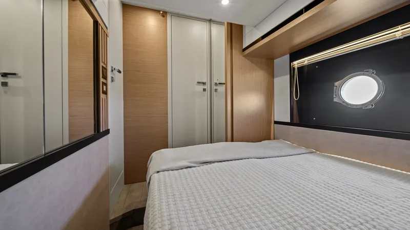 Slide: The Image of Cozy Guest Stateroom This inviting guest stateroom on the Absolute Navetta 58 features a plush double bed with elegant bedding, creating a serene retreat. The space is illuminated by natural light through a stylish porthole, complemented by warm wood finishes and sleek built- - 7018630