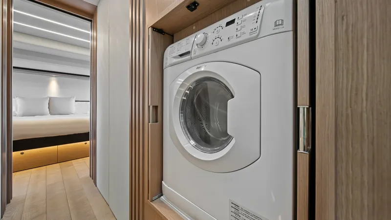 Slide: The Image of Laundry Area with Washer/Dryer Unit This image showcases the convenient laundry area aboard the Absolute Navetta 58, featuring a modern washer/dryer unit seamlessly integrated into a wooden cabinet. The sleek design blends functionality with the yacht's elegant interior aesthetics. Beyond t - 7018651