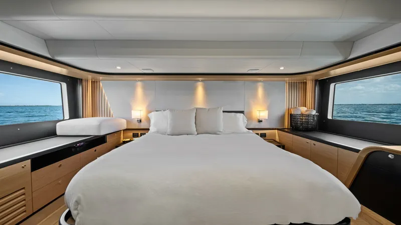 Slide: The Image of Master Stateroom with Panoramic Views The master stateroom of the 2026 Absolute Navetta 58 offers a luxurious retreat, featuring a spacious queen-sized bed with plush linens. Large panoramic windows flood the space with natural light and provide stunning ocean views. Elegant wood finishes and - 7018615