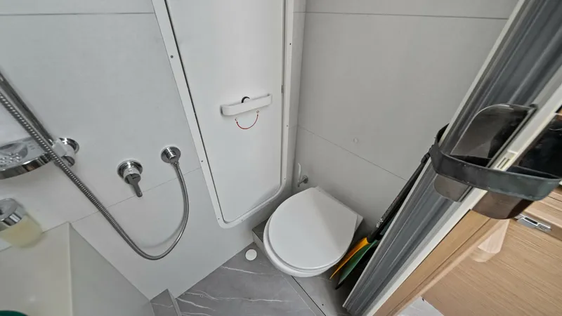 Slide: The Image of Compact Bathroom with Shower The bathroom on the Absolute Navetta 58 offers a compact, efficient layout. It features modern fixtures, a sleek showerhead, and a contemporary toilet, all designed with space-saving in mind. The elegant finish and thoughtful design ensure functionality a - 7018680