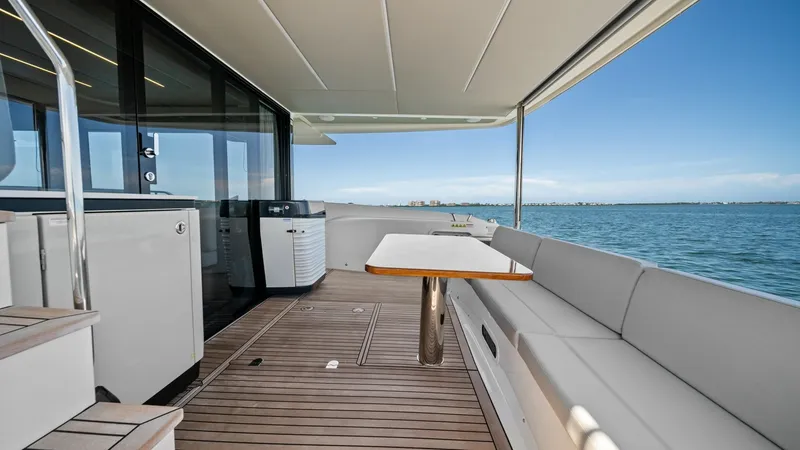 Slide: The Image of Spacious Aft Deck with Seating The aft deck of the Absolute Navetta 58 offers a generous seating area with plush cushions and a sleek wooden table, perfect for alfresco dining. The teak flooring adds a touch of elegance, while the expansive views of the surrounding waters provide a ser - 7018655