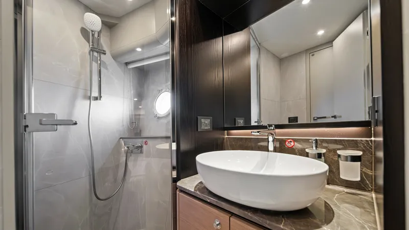 Slide: The Image of Luxurious En-Suite Bathroom The en-suite bathroom on the Absolute Navetta 58 exudes modern elegance with its sleek design. Featuring a stylish vessel sink atop a marble countertop and a separate glass-enclosed shower area, it offers both functionality and luxury. Ambient lighting an - 7018635