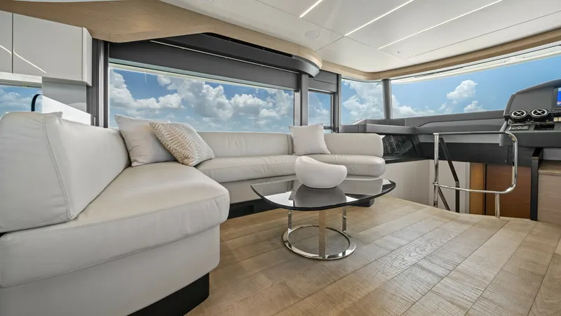 Slide: The Image of Spacious Salon with Panoramic Views The salon of the Absolute Navetta 58 offers an inviting and luxurious space with ample natural light from the expansive windows. The elegant L-shaped sofa provides comfortable seating, complemented by a stylish coffee table. The light wood flooring and mo - 7018621