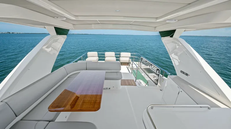 Slide: The Image of Spacious Flybridge Seating Area The flybridge of the Absolute Navetta 58 offers a luxurious seating area with plush, wrap-around couches and a polished wooden table, perfect for entertaining. The open layout provides panoramic views of the ocean, enhancing the outdoor experience. Ample - 7018660