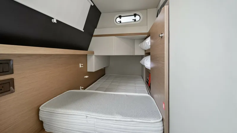 Slide: The Image of Compact Guest Cabin This cozy guest cabin on the Absolute Navetta 58 features a minimalist design with a comfortable berth and ample storage. The light wood finishes and soft lighting create an inviting atmosphere. A small porthole provides natural light and a touch of elega - 7018678