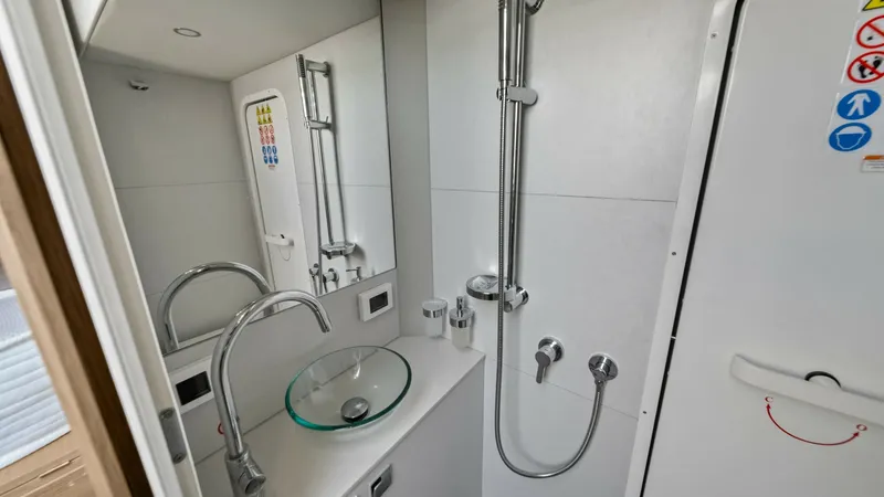Slide: The Image of Compact Ensuite Bathroom This sleek ensuite bathroom on the Absolute Navetta 58 showcases a modern design with a glass vessel sink and contemporary fixtures. The efficient layout includes a streamlined shower area with polished chrome accents, enhancing the overall elegance. Brig - 7018679