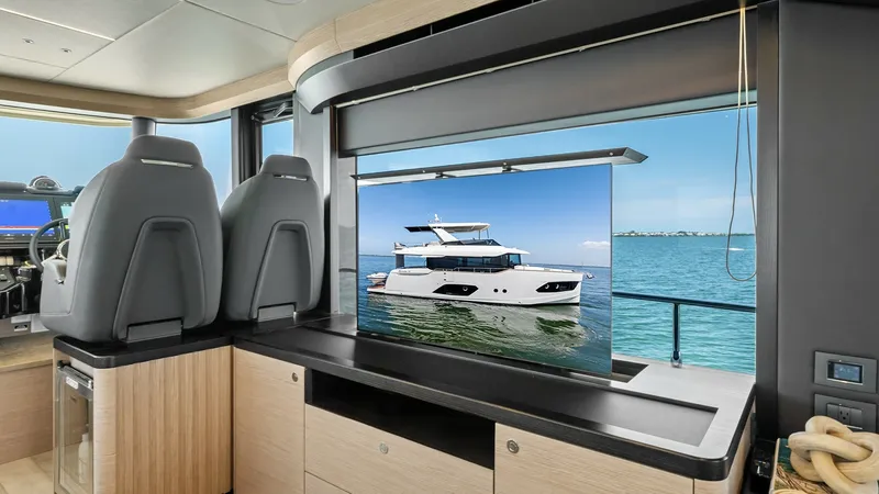 Slide: The Image of Salon with Pop-Up TV and Helm This elegant salon on the 2026 Absolute Navetta 58, ANDIAMO, features a sleek pop-up television, seamlessly integrated into the cabinetry for a clean aesthetic. The helm station offers ergonomic seating with panoramic views, enhancing navigation comfort. - 7018658