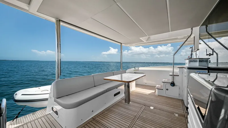 Slide: The Image of Aft Deck with Ocean View Experience luxury on the aft deck of the 2026 Absolute Navetta 58. This spacious area features elegant teak flooring and a comfortable seating arrangement perfect for alfresco dining. Enjoy panoramic ocean views under the shade of the retractable canopy, - 7018652