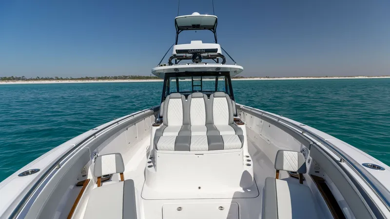 Slide: The Image of Forward Seating Area with Helm View This image showcases the elegant forward seating area of the 2023 Everglades 455 Center Console. The spacious layout features plush, striped upholstery that complements the sleek lines of the boat. In the background, the well-equipped helm station is visi - 7095081