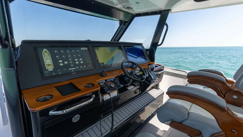 Slide: The Image of Helm Station with Dual Screens The helm station of the 2023 Everglades 455 Center Console, 'Cash Cow,' features dual high-definition navigation screens set within a sleek, modern dashboard. Rich wood accents complement the ergonomic design, providing both style and functionality. Premi - 7095067