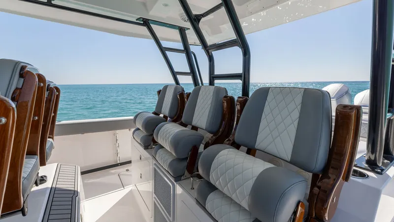Slide: The Image of Helm Seating with Ocean View This image showcases the luxurious helm seating area of the 2023 Everglades 455 Center Console. The plush, diamond-stitched seats provide comfort and style, complemented by the elegant wood accents. Large windows offer a breathtaking panoramic ocean view, - 7095070