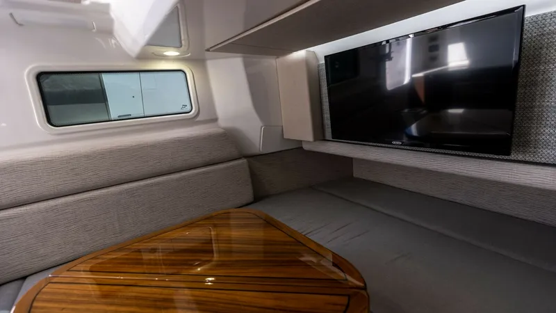 Slide: The Image of Luxurious Cabin Lounge Area This inviting cabin lounge on the 2023 Everglades 455 Center Console features plush seating and a sleek, high-gloss wooden table, perfect for relaxation or entertainment. The integrated flat-screen TV offers modern convenience, while the ample natural lig - 7095073