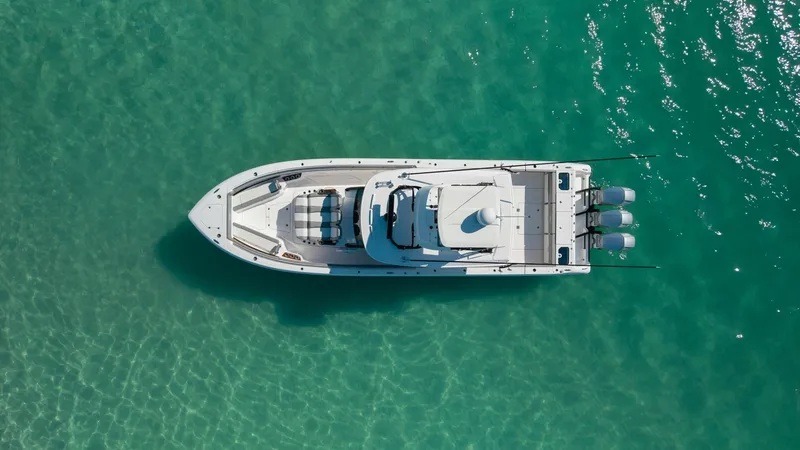 Slide: The Image of Aerial View of Center Console This aerial shot showcases the sleek design of the 2023 Everglades 455 Center Console. The vessel features a spacious deck layout, ideal for both relaxation and entertaining, with ample seating at the bow and helm area. The triple outboard engines promise - 7095093