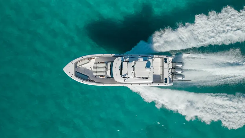 Slide: The Image of Aerial View of Center Console in Motion This aerial shot captures the 2023 Everglades 455 Center Console in action, slicing through turquoise waters with precision and power. The vessel's sleek design and spacious deck layout are complemented by its robust outboard engines, ensuring a smooth an - 7095101