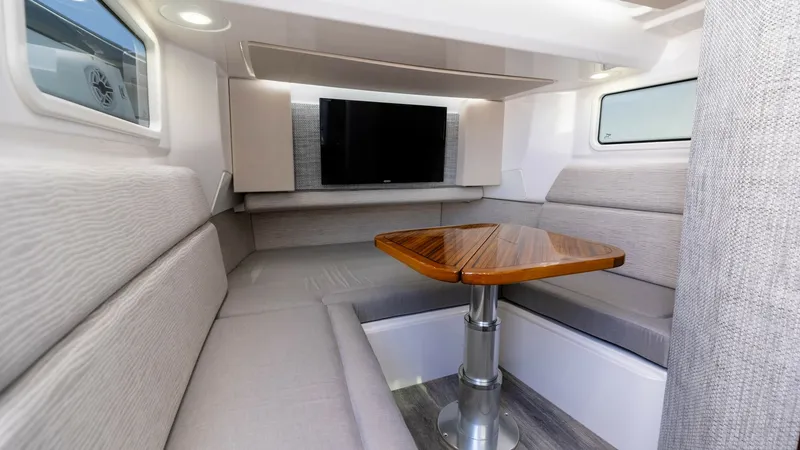 Slide: The Image of Spacious Interior Dinette Area The dinette area of the 2023 Everglades 455 Center Console, 'Cash Cow', offers a welcoming and stylish space for relaxation and dining. It features plush, light-colored seating surrounding a beautifully crafted wooden table, complemented by sleek modern f - 7095061