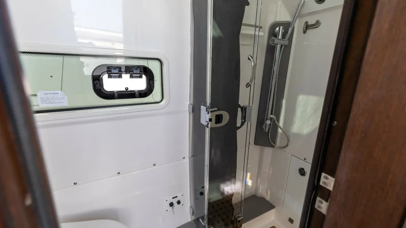 Slide: The Image of Modern Enclosed Bathroom Area This image showcases the sleek and modern bathroom area of the 2023 Everglades 455 Center Console. The space features a compact yet functional layout with a glass-enclosed shower, offering both privacy and elegance. High-quality finishes and ample lightin - 7095077