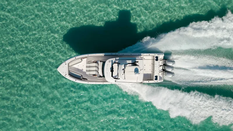 Slide: The Image of Aerial View of Center Console Layout This striking aerial image showcases the 2023 Everglades 455 Center Console, known as 'Cash Cow,' cruising through clear turquoise waters. The vessel's sleek design is emphasized by its spacious deck layout, accommodating multiple seating areas for relaxa - 7095102