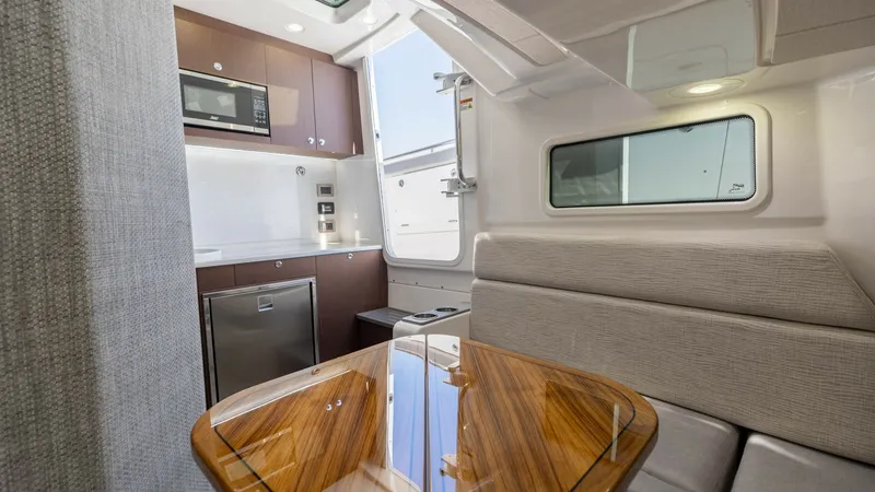 Slide: The Image of Galley and Dinette Area This inviting galley and dinette area on the 2023 Everglades 455 Center Console features elegant wood finishes and contemporary design. The space is equipped with a sleek microwave, a compact refrigerator, and ample storage. Natural light floods in throug - 7095075