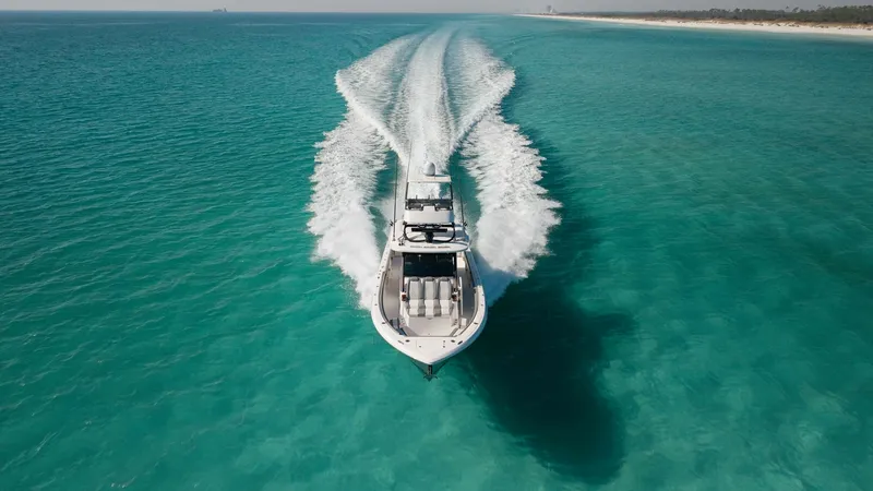 Slide: The Image of Aerial View of Bow at Speed The 2023 Everglades 455 Center Console, 'Cash Cow', cuts through the crystal-clear waters with remarkable agility and power. The sleek bow design ensures a smooth ride, while the spacious deck layout offers ample seating for comfort. This image captures t - 7095098