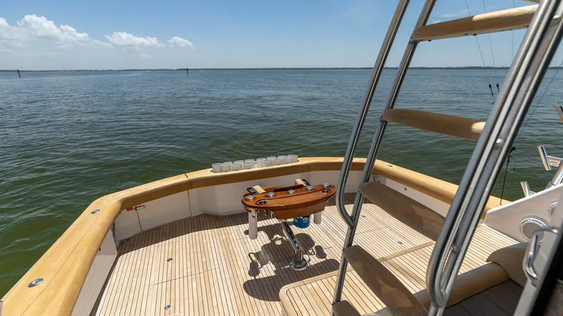 Slide: The Image of Spacious Aft Deck with Ladder Access The aft deck of the 2016 Viking 80 Convertible offers a generous space with teak flooring and a central fighting chair, perfect for avid anglers. The area is surrounded by sturdy railings and features a ladder leading to the upper deck, providing seamless - 7150202