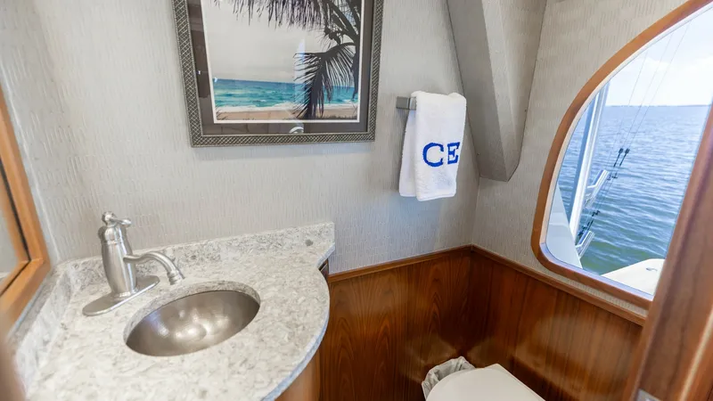 Slide: The Image of Elegant Guest Head with Ocean View This guest head on the 2016 Viking 80 Convertible combines luxury and functionality. It features a sleek, curved granite countertop with an undermount sink and modern chrome fixtures. The wood paneling adds warmth, while a window offers a stunning ocean v - 7150163