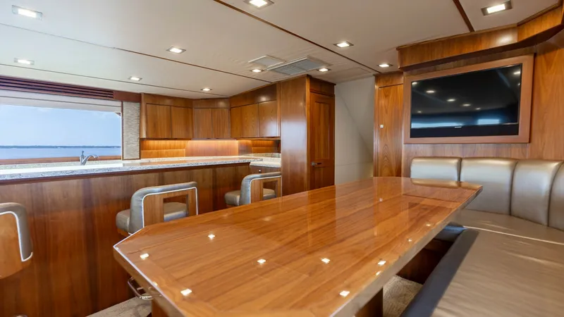 Slide: The Image of Spacious Salon and Dining Area The salon of the 2016 Viking 80 Convertible showcases a luxurious dining area with a beautifully crafted wooden table and plush seating. Elegant cabinetry and modern integrated appliances enhance the space, while large windows provide stunning views and n - 7150169