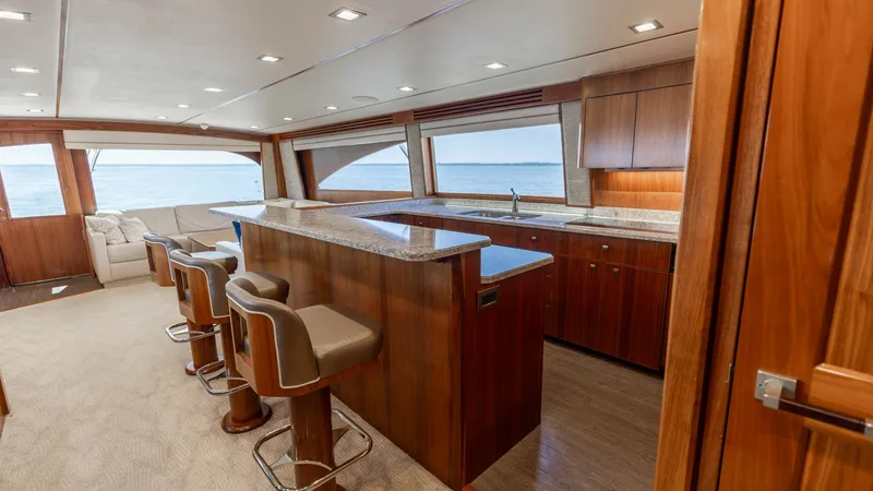Slide: The Image of Spacious Interior Salon and Galley The 2016 Viking 80 Convertible showcases a luxurious interior salon with an open galley design. Rich wood finishes and ample natural light create an inviting atmosphere, complemented by comfortable bar seating and expansive ocean views. This space is perf - 7150167