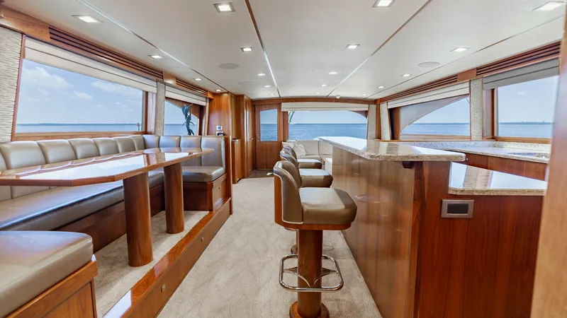 Slide: The Image of Spacious Main Salon and Dining Area The main salon of this 2016 Viking 80 Convertible offers an inviting atmosphere with elegant wood finishes and plush seating. Expansive windows provide panoramic ocean views, flooding the space with natural light. The layout includes a comfortable dining - 7150158