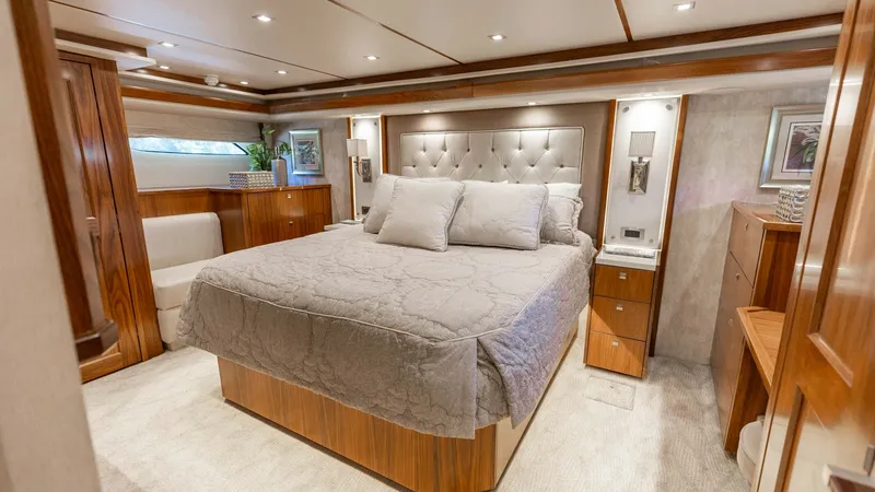Slide: The Image of Luxurious Master Stateroom Interior This master stateroom on the 2016 Viking 80 Convertible exudes elegance and comfort. The room features a plush, queen-sized bed with a tufted headboard, surrounded by rich wooden cabinetry and soft, ambient lighting. Large windows allow natural light to f - 7150180