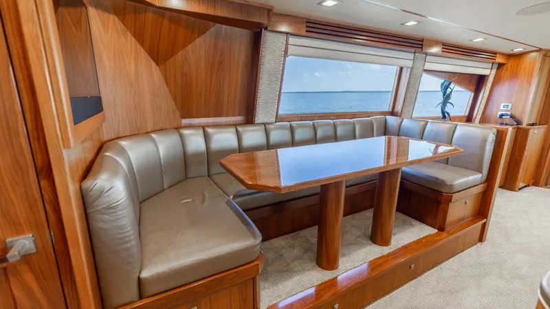 Slide: The Image of Elegant Dinette with Ocean View This inviting dinette area on the 2016 Viking 80 Convertible features plush leather seating and a polished wood table, perfect for dining or entertaining. Large windows provide stunning ocean views, enhancing the open and airy ambiance. The rich wood fini - 7150170
