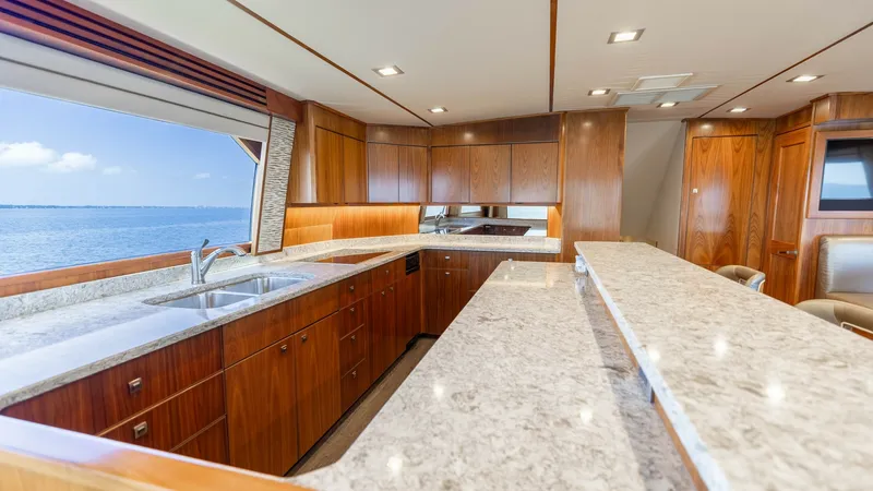 Slide: The Image of Galley with Expansive Countertops This 2016 Viking 80 Convertible features a well-appointed galley with expansive granite countertops, offering ample space for meal preparation and entertaining. The rich wood cabinetry provides abundant storage while complementing the elegant design. Larg - 7150168