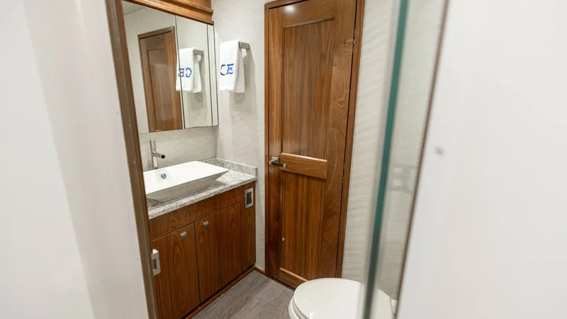 Slide: The Image of Elegant En-Suite Bathroom This sophisticated en-suite bathroom on the 2016 Viking 80 Convertible features warm wooden cabinetry and a sleek, modern sink. The space is enhanced by polished fixtures and a large mirror, creating an open and inviting atmosphere. High-quality materials - 7150197
