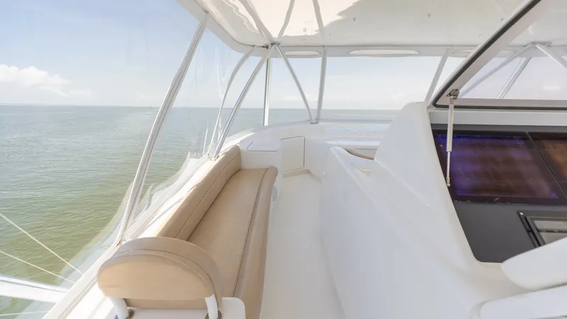 Slide: The Image of Flybridge Seating with Ocean View This image showcases the spacious flybridge seating area on the 2016 Viking 80 Convertible. The elegant bench seating is wrapped in premium upholstery, offering comfort while enjoying panoramic ocean views. The surrounding glass enclosure ensures a protec - 7150205