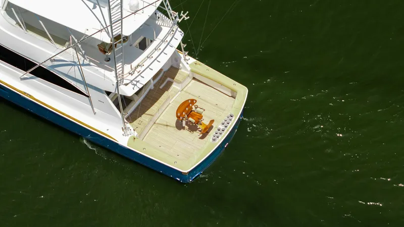 Slide: The Image of Aerial View of Spacious Aft Deck This image showcases the expansive aft deck of the 2016 Viking 80 Convertible, featuring a premium teak finish. The deck is equipped with a centrally positioned fighting chair, ideal for deep-sea fishing enthusiasts. Ample space and strategic layout make - 7150215