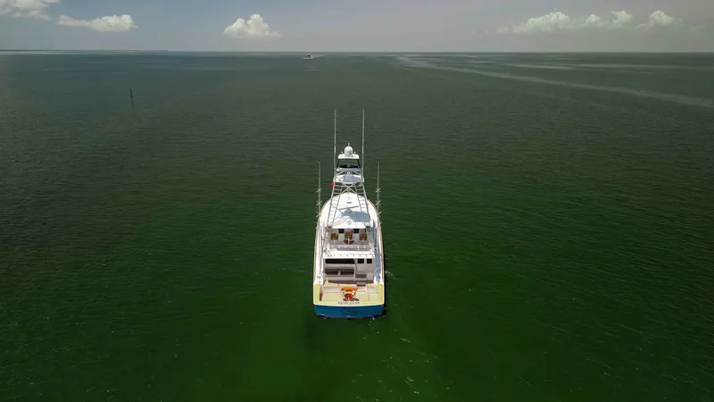 Slide: The Image of Aerial Stern View on Open Water The 2016 Viking 80 Convertible is captured from above, showcasing its elegant stern as it glides through open water. The vessel's expansive deck space is highlighted, emphasizing its suitability for both leisure and sportfishing. The serene, wide ocean ba - 7150216