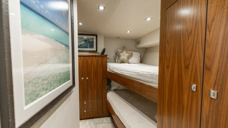 Slide: The Image of Guest Cabin with Bunk Beds This cozy guest cabin on the 2016 Viking 80 Convertible features elegant wooden finishes and comfortable bunk beds, perfect for accommodating guests. The space is well-lit with recessed lighting, enhancing the warm tones of the cabinetry and walls. A scen - 7150196