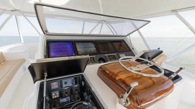 Slide: The Image of Flybridge Helm Station This image showcases the helm station of the Viking 80 Convertible, featuring state-of-the-art navigation systems and a beautifully crafted wooden steering wheel. The console is equipped with multiple multifunction displays, providing comprehensive contro - 7150206
