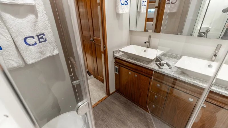 Slide: The Image of Elegant Ensuite Bathroom with Dual Sinks This sophisticated ensuite bathroom on the 2016 Viking 80 Convertible features dual rectangular sinks set atop a sleek, polished stone countertop. The rich wood cabinetry adds warmth and elegance, while the glass-enclosed shower enhances the modern design - 7150184