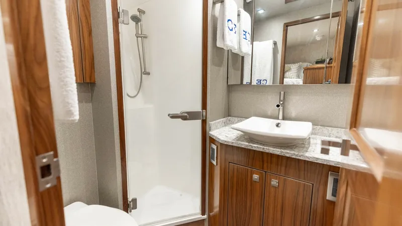 Slide: The Image of Luxurious Ensuite Bathroom This elegant bathroom on the 2016 Viking 80 Convertible features a modern glass-enclosed shower and a sleek vessel sink. The warm wood cabinetry paired with high-quality fixtures provides a luxurious and inviting atmosphere. Ample lighting and sophisticat - 7150192