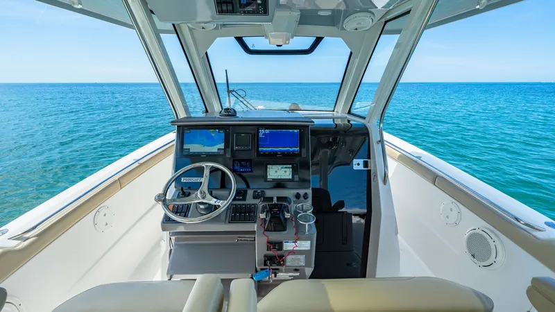 Slide: The Image of Helm Station with Panoramic View The helm station of the 2019 Pursuit 328 model, Orcabessa, features state-of-the-art navigation technology with dual display screens and a sleek steering wheel. The expansive windshield offers a panoramic view of the open sea, enhancing the captain's expe - 7095008