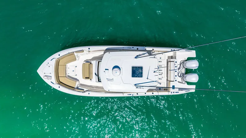 Slide: The Image of Aerial View of Pursuit 328 Deck This aerial shot of the 2019 Pursuit 328 showcases its spacious deck layout. The vessel features ample seating at the bow, perfect for relaxing or entertaining. Twin outboard engines are visible at the stern, highlighting the boat's powerful performance c - 7095019